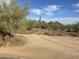 Long dirt driveway leading up to a desert property with natural landscaping at 7100 E Montgomery Rd, Scottsdale, AZ 85266