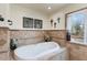 Serene bathroom with a soaking tub, decorative tiles, and a large window with natural light at 7100 E Montgomery Rd, Scottsdale, AZ 85266