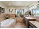 Relaxing bathroom showcasing a soaking tub, dual vanity, decorative sconces, and natural light at 7100 E Montgomery Rd, Scottsdale, AZ 85266