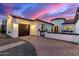 Charming home featuring a terracotta roof, a two-car garage, and decorative stonework, all under a colorful twilight sky at 8418 W Louise Ct, Peoria, AZ 85383