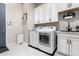 Well-lit laundry room with white cabinets, modern appliances, and a utility sink at 8418 W Louise Ct, Peoria, AZ 85383