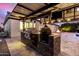 This outdoor kitchen features stainless steel appliances, stone accents, and a flat-screen television at 8418 W Louise Ct, Peoria, AZ 85383