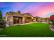 Expansive backyard with lush green lawn, covered patio, and an outdoor dining area under a colorful twilight sky at 9955 E Celtic Dr, Scottsdale, AZ 85260