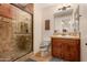 An elegant bathroom with a glass-enclosed shower, oak cabinets, and earth tone tile at 9955 E Celtic Dr, Scottsdale, AZ 85260