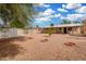 Spacious gravel backyard featuring mature trees, fire pit, and covered patio perfect for outdoor entertaining at 1004 S Ironwood Dr, Apache Junction, AZ 85120