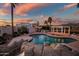 Aerial view of the home's backyard with lush lawn, pool, and covered patio at dusk at 10301 N 128Th St, Scottsdale, AZ 85259