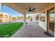 Covered patio features brick pavers, ceiling fan, and view of the built in outdoor kitchen and green yard at 10301 N 128Th St, Scottsdale, AZ 85259