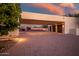 Three-car garage and extra parking on brick drive with a basketball and tennis court beyond at 10301 N 128Th St, Scottsdale, AZ 85259