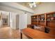 Home office with built-in shelves, a desk, and tile floors with an adjacent hallway at 10301 N 128Th St, Scottsdale, AZ 85259