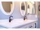 Modern bathroom featuring dual sinks, white cabinetry, and elegant oval mirrors at 1054 W Park Ave, Gilbert, AZ 85233