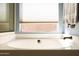 Close up of the relaxing soaking tub with bronze fixture and a window at 1054 W Park Ave, Gilbert, AZ 85233