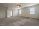 Spacious bedroom features a ceiling fan, two windows, and neutral carpet at 10705 E Sunflower Ct, Florence, AZ 85132