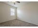 This bedroom features neutral carpeting, a ceiling fan, and a window for natural light at 10705 E Sunflower Ct, Florence, AZ 85132