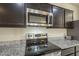 Close-up of a kitchen with stainless steel appliances, granite countertops, and dark wood cabinets at 10705 E Sunflower Ct, Florence, AZ 85132