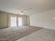 Spacious living room featuring plush carpet flooring, ample light, and modern ceiling fan at 10705 E Sunflower Ct, Florence, AZ 85132