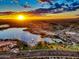 Stunning aerial view of the community, highlighting a lake, fountains, pools, and surrounding landscape at sunset at 11256 S Hopi Dr, Goodyear, AZ 85338