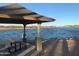 Covered lakeside picnic area with a wood picnic table offering a tranquil view of the lake and surrounding houses at 11256 S Hopi Dr, Goodyear, AZ 85338