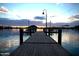 Picturesque dock view on the lake at dusk, featuring benches and lamp posts for a relaxing ambiance at 11256 S Hopi Dr, Goodyear, AZ 85338