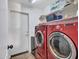 Laundry room with red washer and dryer set, white door and wall shelving at 11256 S Hopi Dr, Goodyear, AZ 85338