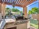 Outdoor kitchen with built-in grill, putting green and well manicured backyard at 11256 S Hopi Dr, Goodyear, AZ 85338