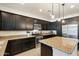 Modern kitchen featuring dark cabinets, stainless steel appliances, and a granite island with pendant lighting at 12038 W Briles Rd, Peoria, AZ 85383