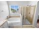 Bright bathroom with a large tub next to the window and a shower stall with glass doors at 12163 W Chase Ln, Avondale, AZ 85323