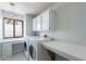 Bright laundry room featuring a large window, overhead cabinets, and folding table at 1219 E Seminole Dr, Phoenix, AZ 85022