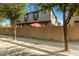 A cozy two-story condo featuring a red patio umbrella, framed by mature trees and a secure block wall at 1458 N 80Th Ln, Phoenix, AZ 85043