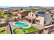 Aerial view displaying a sparkling backyard pool, manicured putting green, and patio dining set at 18225 W Mackenzie Dr, Goodyear, AZ 85395