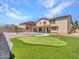 Lush backyard featuring a refreshing swimming pool, putting green, and meticulously landscaped grounds at 18225 W Mackenzie Dr, Goodyear, AZ 85395