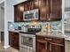 A kitchen features dark wood cabinets, stainless appliances, granite countertops and tile backsplash at 18225 W Mackenzie Dr, Goodyear, AZ 85395