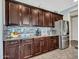 A kitchen features dark wood cabinets, granite countertops, stainless appliances and tile backsplash at 18225 W Mackenzie Dr, Goodyear, AZ 85395