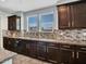 A kitchen features dark wood cabinets, tile backsplash, granite countertops, and stainless appliances at 18225 W Mackenzie Dr, Goodyear, AZ 85395