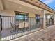 View of the covered patio with tile flooring, a table and chairs, and a black wrought iron fence at 18225 W Mackenzie Dr, Goodyear, AZ 85395