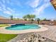 Backyard view of the pool with a landscaped rock border and artificial turf at 18225 W Mackenzie Dr, Goodyear, AZ 85395