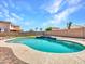 Backyard view of the pool, landscaped rock border, artificial turf, and surrounding block fence at 18225 W Mackenzie Dr, Goodyear, AZ 85395