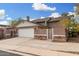 Side view of a one-story home with a brick wall, lush bougainvillea and two-car garage at 1938 N 67Th St, Mesa, AZ 85205