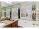 Bathroom with a soaking tub, granite counters, wood cabinets and plantation shutters at 19927 N 108Th Ln, Sun City, AZ 85373