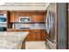 Kitchen featuring stainless appliances, custom wood cabinets, granite counters, and tile flooring at 19927 N 108Th Ln, Sun City, AZ 85373