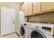 Bright laundry room with side-by-side washer and dryer units and ample overhead storage at 19927 N 108Th Ln, Sun City, AZ 85373