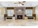 Cozy living room featuring a fireplace with custom stone mantle, built-in seating, and neutral color palette at 19927 N 108Th Ln, Sun City, AZ 85373