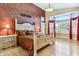 View of the bedroom with red accent wall, light wood floors, large window, and bright chandelier at 19927 N 108Th Ln, Sun City, AZ 85373