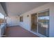 Covered patio area with a red concrete floor, white brick wall, and a sliding glass door at 2507 E Golden St, Mesa, AZ 85213