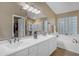 A bathroom featuring double sinks, a bathtub with a shower, and a walk-in closet visible through the doorway at 3482 W Shannon St, Chandler, AZ 85226