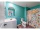 A turquoise bathroom with a white vanity, toilet, shower with curtain and arched mirror at 40564 W Nicole Ct, Maricopa, AZ 85138