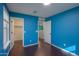 A blue-walled bedroom with hardwood floors, two doorways and one window with white blinds at 40564 W Nicole Ct, Maricopa, AZ 85138