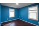 Bedroom with two windows and dark wood-look flooring at 40564 W Nicole Ct, Maricopa, AZ 85138