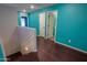 Hallway with dark wood-look floors, white trim, and turquoise walls at 40564 W Nicole Ct, Maricopa, AZ 85138