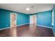 A blue-walled main bedroom with hardwood floors, three doorways, and a window with natural lighting at 40564 W Nicole Ct, Maricopa, AZ 85138