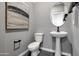 Powder bathroom with gray walls, pedestal sink, round mirror, and artwork on the wall at 44327 N 43Rd Dr, Phoenix, AZ 85087